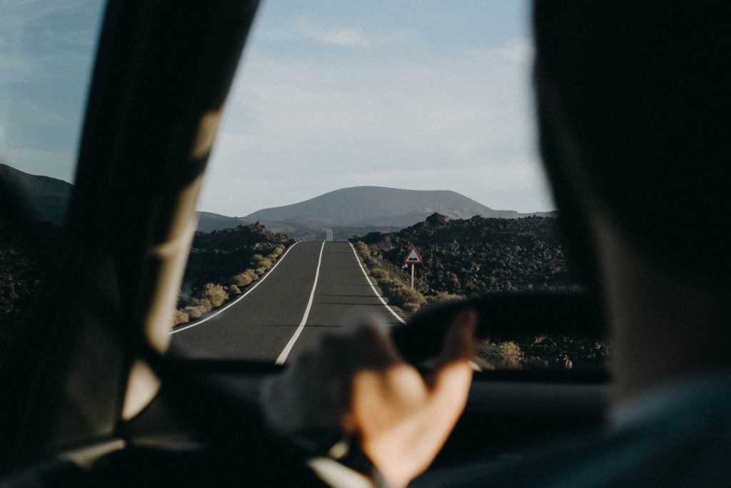 personne au volant qui pilote sa voiture au milieu d'une route