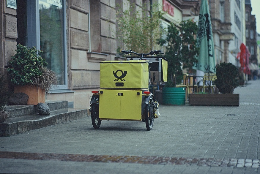 Tricycle de livraison jaune garé devant une entrée d'immeuble illustrant ce qu'est le dernier kilomètre