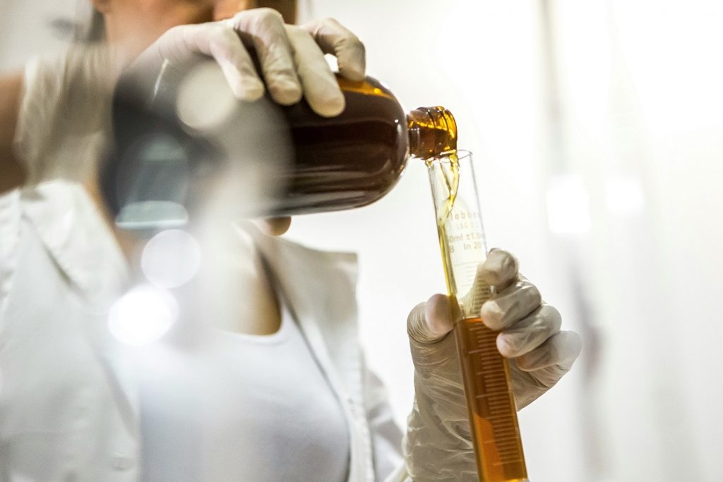 Impacts du mode de production sur la supply chain illustré par une femme versant un liquide dans un tube à essai