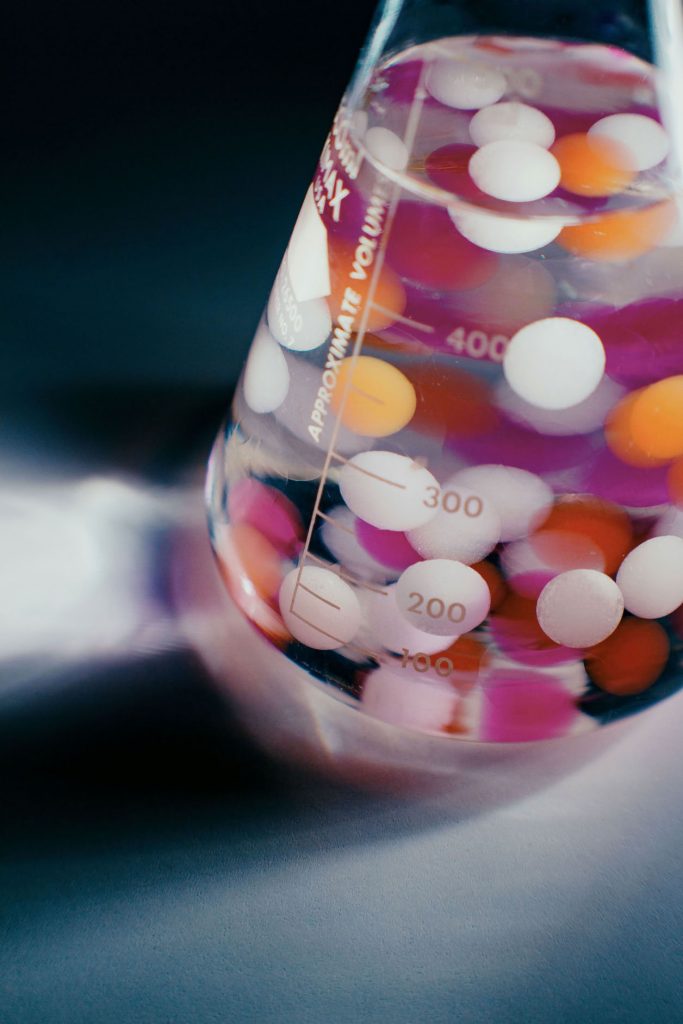 éprouvette pharmaceutique contenant pastilles de couleurs pour illustrer l'article - 3PL ou internalisation : jusqu'où sous-traiter sa logistique en pharma et cosmétique ?