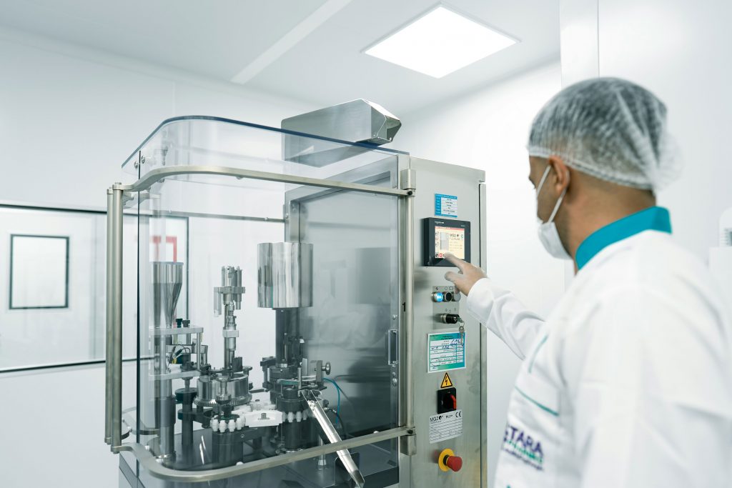Un opérateur utilisant des machines dans une salle blanche pour illustrer ECM pharmaceutique et cosmétique