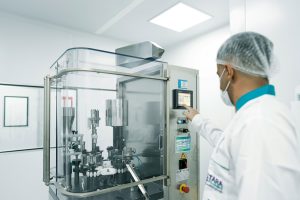 Un opérateur utilisant des machines dans une salle blanche pour illustrer ECM pharmaceutique et cosmétique