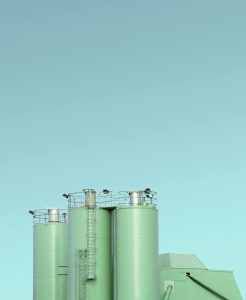 Vue de cuves et réservoirs verts d'une usine industrielle de chimie ou pharma sur ciel bleu