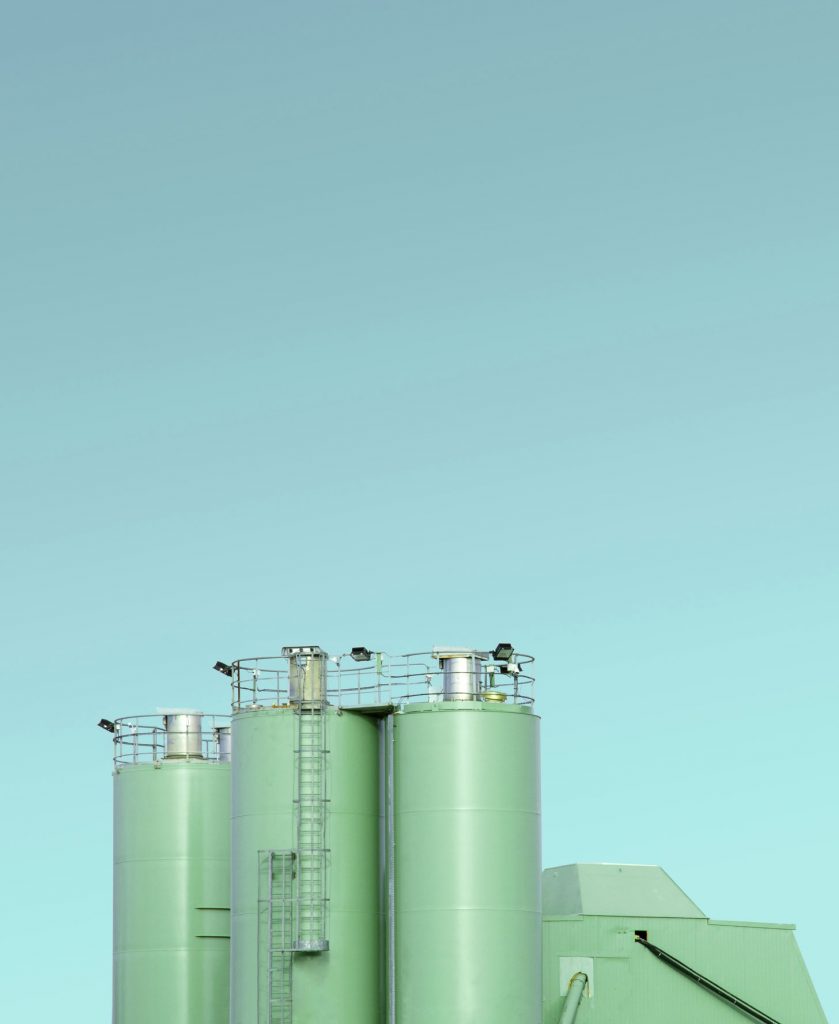 Vue de cuves et réservoirs verts d'une usine industrielle de chimie ou pharma sur ciel bleu