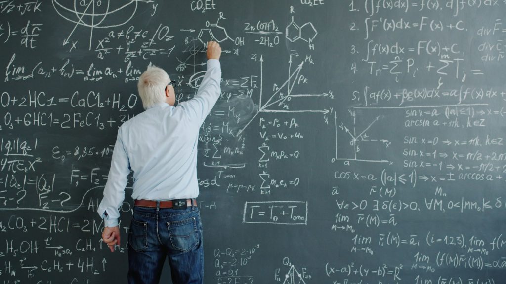 un professeur &eacute;crivant des formules complexes sur un tableau noir illustrant les pr&eacute;visions